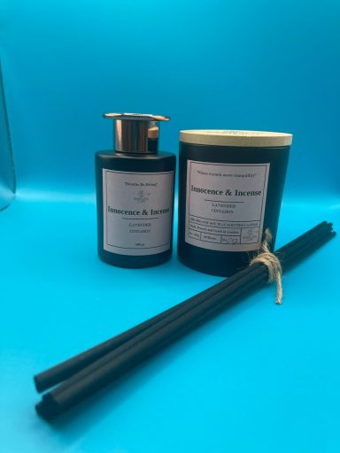 Two black fragrance products with a gold pump, accompanied by black reed sticks.
