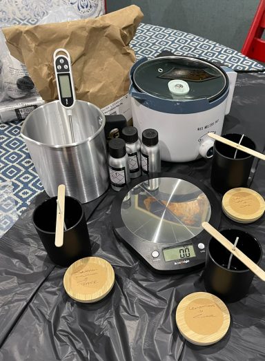 Various candle-making supplies, including a scale, thermometer, and containers.