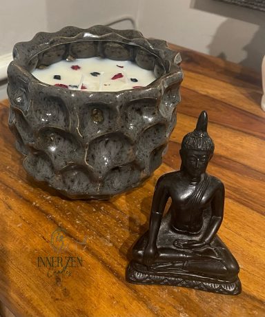 A decorative candle holder and a small Buddha statue on a wooden surface.