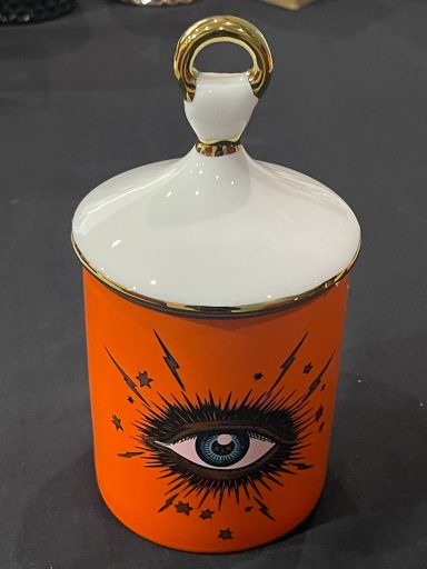 Bright orange container with a white lid, featuring an eye design and decorative accents.