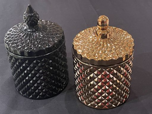 Two decorative lidded jars, one black and one gold, with textured surfaces.