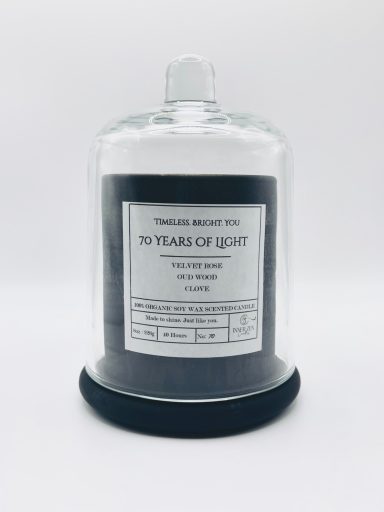 A glass jar containing a candle labelled "10 Years of Light" on a black base.
