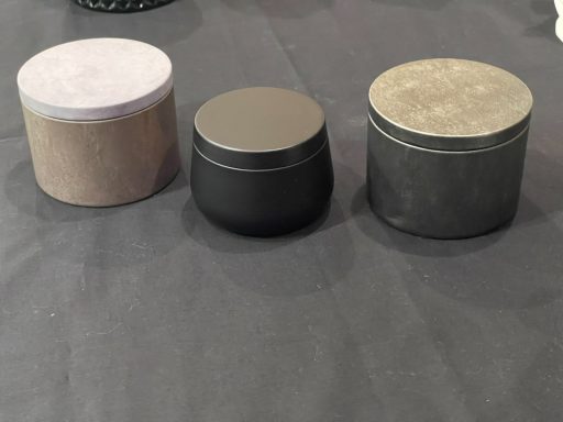 Three cylindrical containers of varying sizes and textures on a dark surface.
