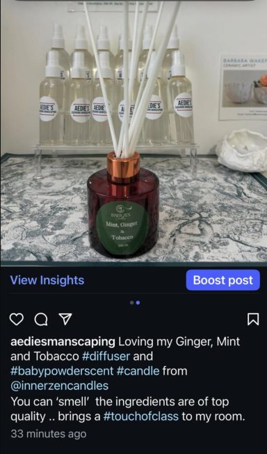 A scented candle in a green jar surrounded by essential oil bottles on a table.